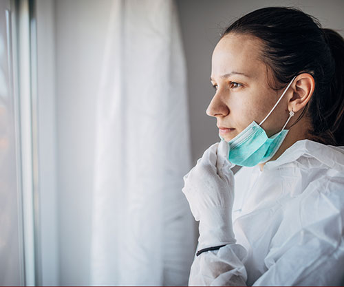 female nurse intenly looking out a window during covid pandemic